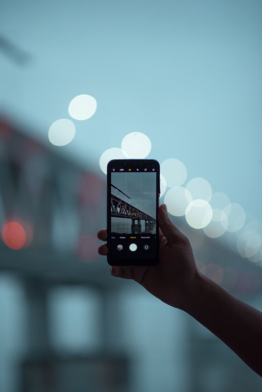 Closeup of a person taking a picture of a bridge, a vertical shot