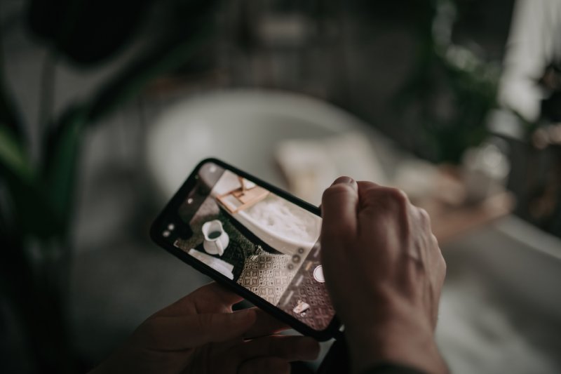 Mans hand take photo by phone for social media luxury interior eco style bathroom with oval bathtub